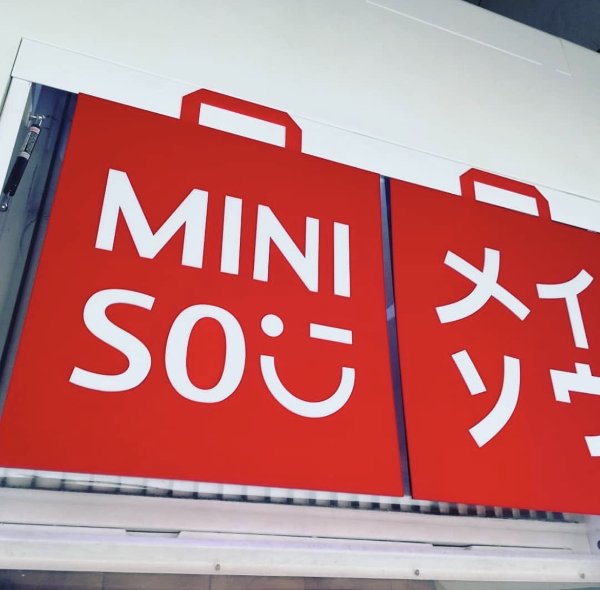 Anuncio de fachada Miniso en acrílico rojo con letras blancas instalado en marquesina