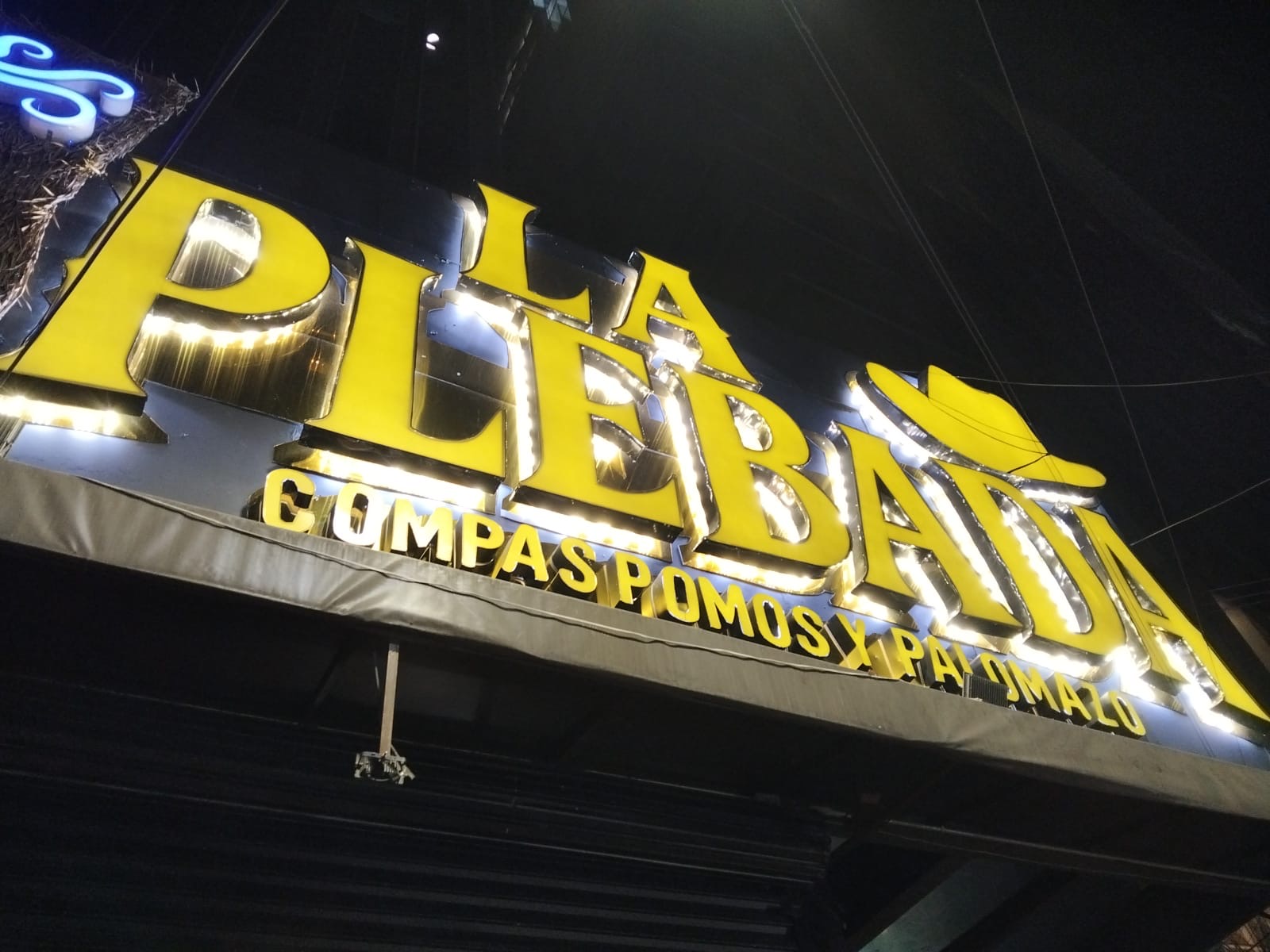 Anuncio luminoso amarillo de La Plebada con acabado metálico fotografiado de noche
